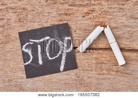 White cigarette with filter broken. Message stop, broken cigarette, wooden background. Stop smoking tobacco cigarettes.