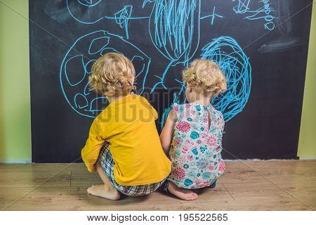 Boy And Girl Paint With Chalk On A Blackboard