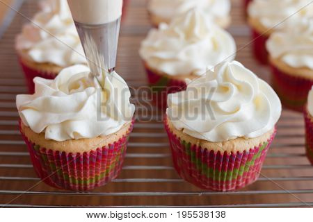 Handmade capcake with cream. Baker decorates muffins with cream and confectionery nozzles
