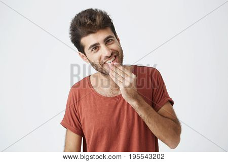 Attractive Caucasian young man pleasant looking at the camera. Cheerful and smiling, demonstrating his white teeth having good mood after getting good news.