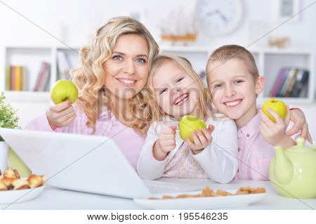 happy mother and children sitting at table with laptop