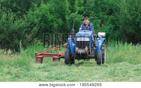 Man harvests hay using a tractor for agriculture