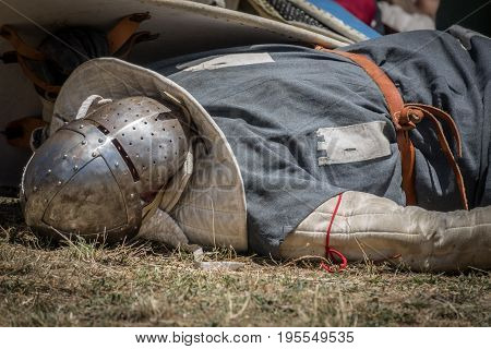 Medieval knight fallen in battle, on a reenactment with costumed characters and medieval armor with chainmail, helmet swords and shields. Medieval demonstration and recreation