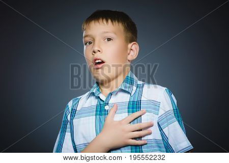 Closeup Portrait of handsome boy with astonished expression while standing against grey background.