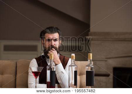 Hipster Sitting At Table With Three Bottles And Glass