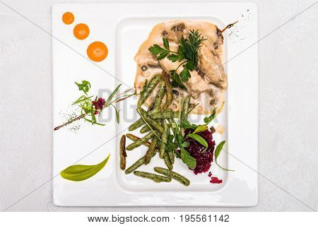 Top view beet salad with chicken meat in sauce decorated in white plate. Restaurant meal.
