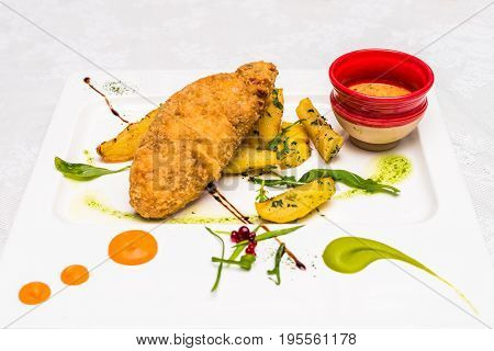Side view chicken meat with potato and sauce decorated in white plate. Restaurant meal.