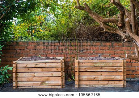 Two wooden compost bins in a back garden.