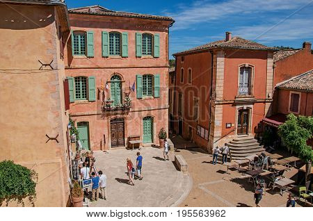 Roussillon, France - July 03, 2016. Traditional colorful houses in ocher and people in the historic city center of Roussillon. Located in the Vaucluse department, Provence region, southeastern France