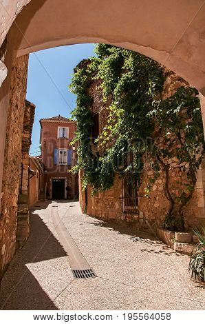 Roussillon, France - July 03, 2016. Traditional colorful houses in ocher under a sunny blue sky, in the historic Roussillon. Located in the Vaucluse department, Provence region, southeastern France