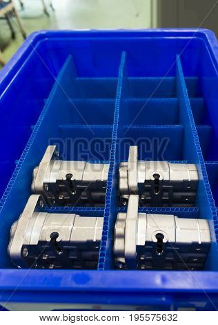 Automotive Aluminium parts kept in a blue plateic box ; parts produced by Low Pressure Die casting process and cnc machining machine