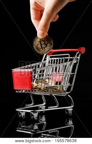 hand throws a bitcoin into trolley.