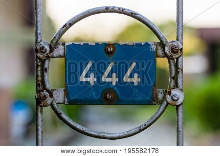 Plate with numbers 444 on the old fence.