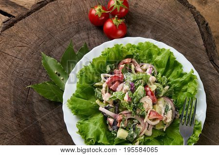 Fresh salad with fresh red cerry tomatoes cucumbers chicken red onion radish bell pepper lettuce with special spisy sauce on wooden table. Healthy eating and diet concept.