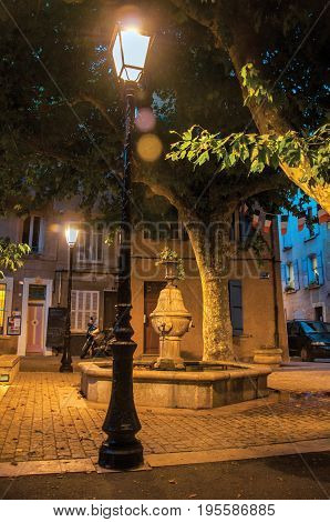Rians, France - July 08, 2016. View of square with fountain in the early evening with lamp lit, at the lovely village of Rians. Located in Var department, Provence region, in southeastern France.