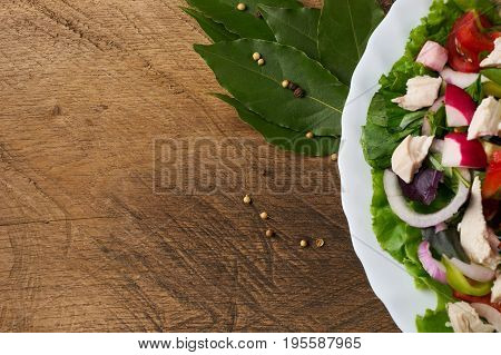Fresh salad with chicken breast radish cucumber tomato onion bell pepper basil mint and other spices on old rustic wooden table. Copy space. Healhy eating. Top view