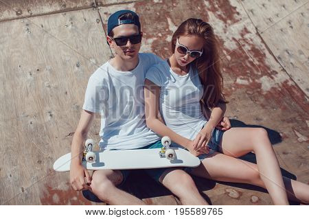 Young skater boy and girl skateboard posing in skate park.