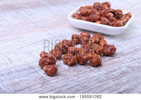 Sugared Hazelnuts in a white bowl on a wooden background. Hazelnuts in sugar glaze. Selective focus