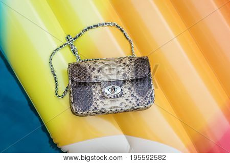 Fashion luxury snakeskin python handbag on a Inflatable Yellow Mattress in Swimming Pool.
