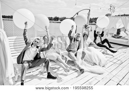 Wedding Couple, Groomsmen And Bridesmaids Having Fun With Balloons On Wharf. Black And White Photo.