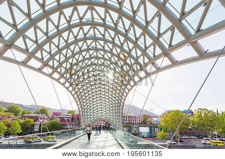 TBILISI GEORGIA - May 01 2017. Tourists and locals walking on modern architectural landmark - Bridge of Peace over Kura river.