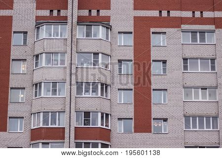 a facade of a russian block of flats in a cloudy weather with balconies and windows
