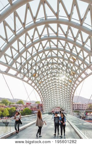 TBILISI GEORGIA - May 01 2017. Tourists and locals walking on modern architectural landmark - Bridge of Peace over Kura river.
