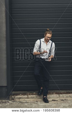 Stylish Young Businessman In Spectacles Holding Ashtray While Smoking