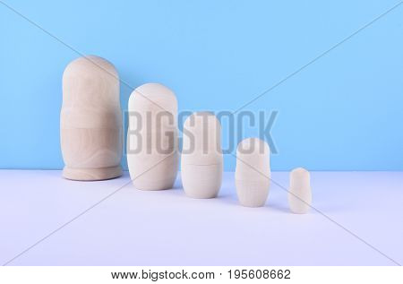 Wooden unpainted russian nested dolls - matryoshka - on blue background. Family concept.