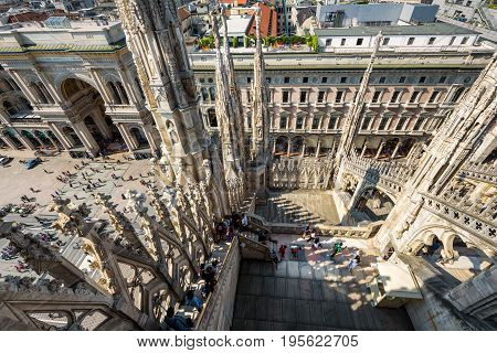 Milan, Italy - May 16, 2017: Tourists visit the roof of the Milan Cathedral (Duomo di Milano). View of the Piazza del Duomo with the Galleria Vittorio Emanuele II from the top of the Milan Duomo.