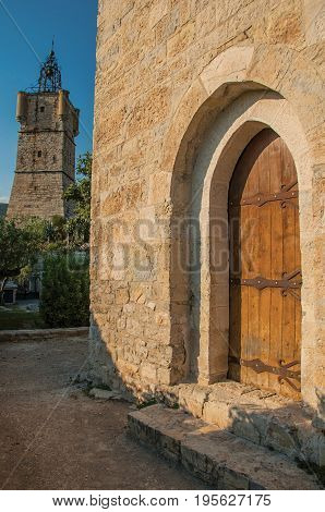 View of the clock tower made of stone on top of the hill and wooden ancient door in the lively and gracious town of Draguignan. Located in the Var department, Provence region, southeastern France