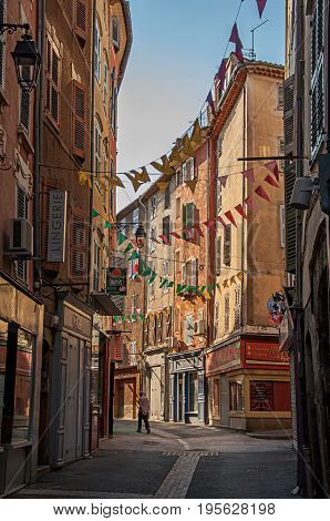 Draguignan, France - July 11, 2016. View of alley with townhouses and pedestrians in the city center of the lively and gracious town of Draguignan. Var department, Provence region, southeastern France