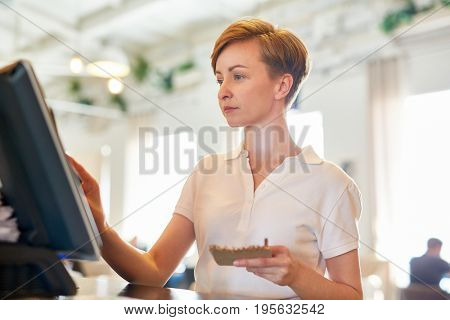 Bistro worker registrating new order by cash-register