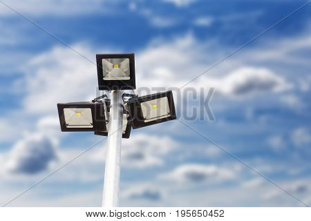 Street LED Light with energy-saving technology on the pole against blurred blue cloudy sky