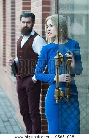 Girl Opening Glass Door With Man Holding Bottle Of Wine