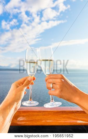 Luxury honeymoon cruise couple toasting champagne. Travel holiday newlyweds drinking with wedding rings holding glasses doing cheers at sunset view of cruise holiday destination.
