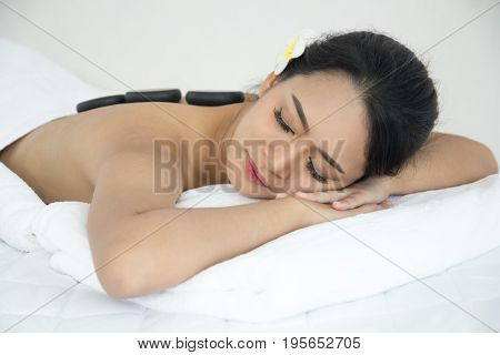 Asian Girl Lay Down On The Bed In Spa With Stone On Back.