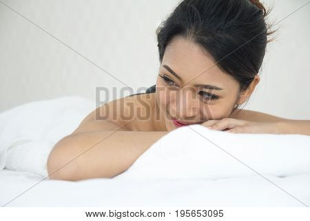 Cheerful Asian Girl Lay Down On The Bed In Spa Waiting For Service Smiling Happily.