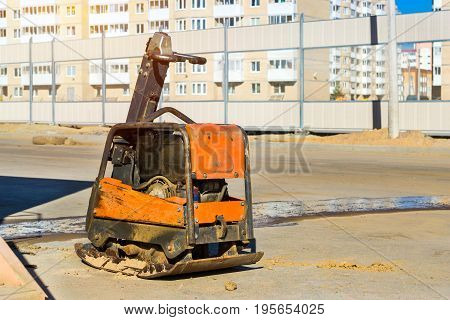 Manual ramming machine for compacting soil on construction of high-speed road around Krasnoe Selo Saint Petersburg. Light mechanized tools and equipment for works at industrial construction. Russia