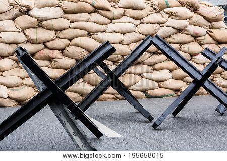 Black steel street barrier in shape of anti-tank Czech hedgehog obstacle defense stands on asphalt urban road