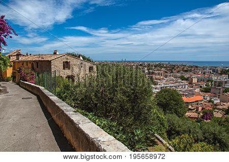 Alley with houses, street on the hill and blue sky in Haut-de-Cagnes, a pleasant village on top of a hill, near Nice. In the Alpes-Maritimes department, Provence region, southeastern France.