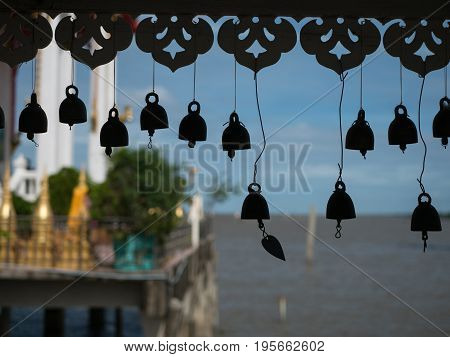Silhouettes of bells attached to the walkway to Wat Hong Thong by visitors for good luck. The temple is built on a concrete platform at the coast of Chachoensao in Thailand after the sea started to reclaim the area of the original temple several decades a