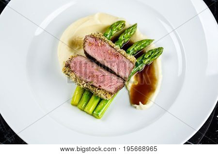 medium done grilled tuna steak with asparagus served on the asparagus and mashpotato