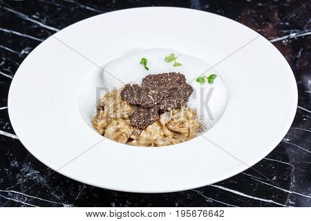 risotto with truffles served in the white plate on the black background