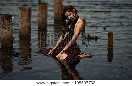 Young woman bathing in therapeutic water of mud estuary, next there are her reflection and wooden columns. Spa.