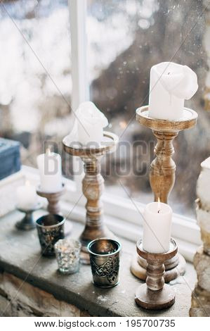 White candles in copper candlesticks on the windowsill