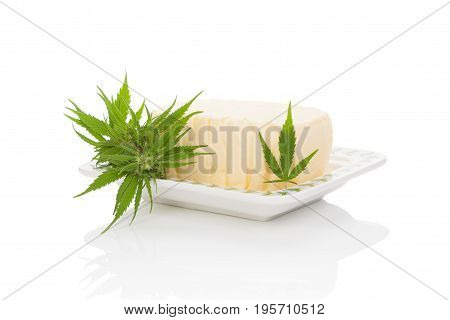 Cannabutter with marijuana leaf on saucer isolated on white background. Cannabis butter natural remedy.