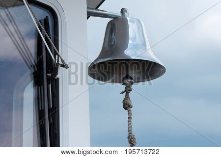 A large silver bell hangs on the outside of a ferry boat