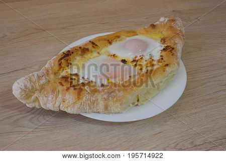 Khachapuri on ajarski - recipe of Georgian cuisine. Adjarian Georgian national dish Khachapuri bread with cheese and egg on a plate in a cafe