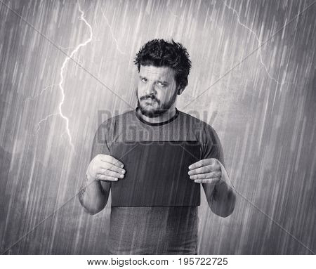 Caught gangster with rainy, grey background and black table on his hand. 